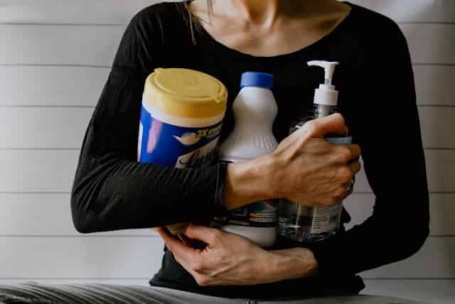 A woman holding bottles of cleaning products